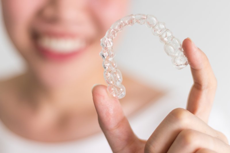 Woman smiling while holding a clear aligner