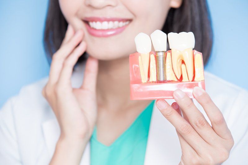 dentist holding a model of dental implants in Allen, TX
