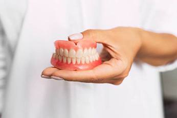 dentist holding a denture