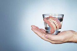 full denture soaking in a glass of water